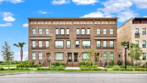 A multi-story brick building with a symmetrical facade, large windows, and a central entrance. - Wharfside Whimsy | 3BR Retreat Walk to River St (Savannah)