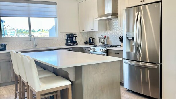Una cocina moderna con una isla central, electrodomésticos de acero inoxidable y vistas al exterior.