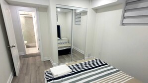 A bedroom with a bed, a mirror, and a door leading to a bathroom. - Brand new 2-bedroom Apartment with  AC/Heat in Brampton (Brampton)
