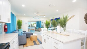 Une cuisine moderne avec des meubles blancs, un îlot central et un coin repas avec des chaises blanches.