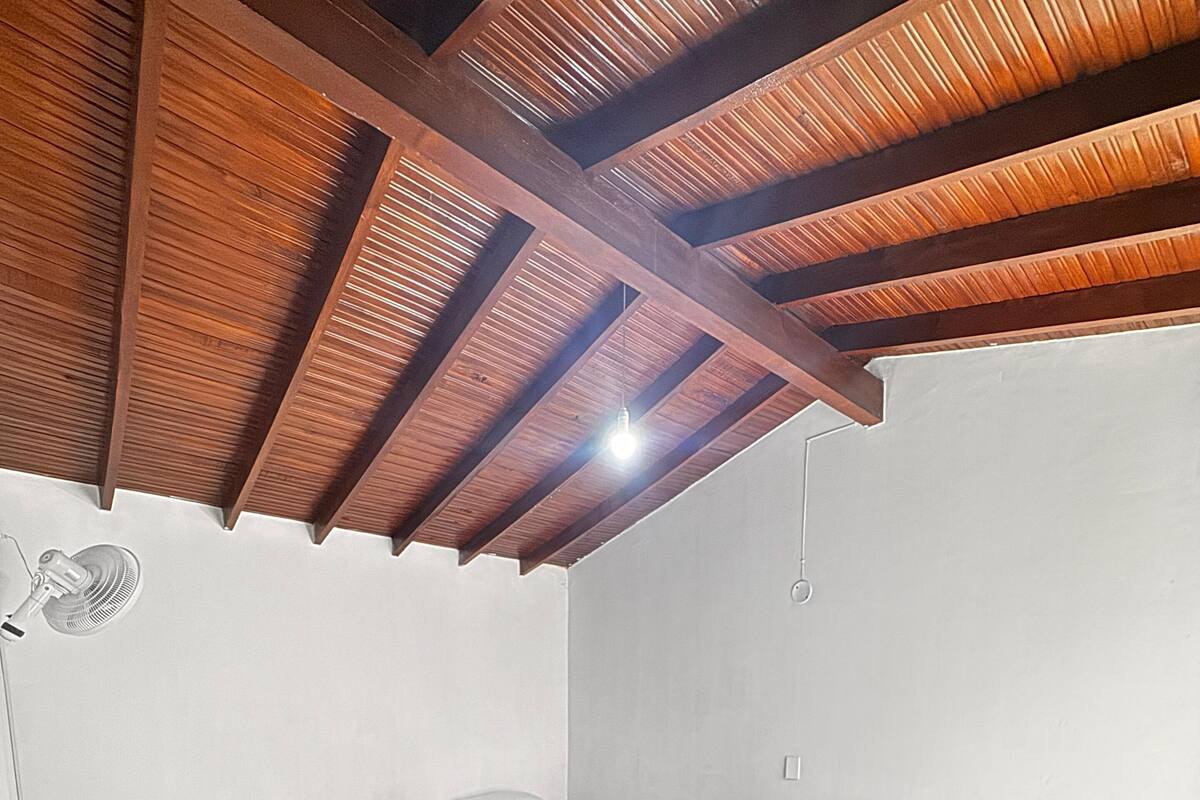 A room with three beds, wooden flooring, and a sloped ceiling with exposed beams.