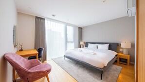 Et moderne hotelværelse med en stor seng, et skrivebord, en stol og et vindue med gardiner.