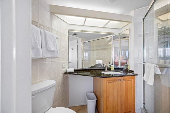 A modern bathroom with a toilet, sink, and shower area. - 💕Lighthouse Towers #706 -Amazing 2BR condo with Gulf Views, Pool, Hot Tub & Amenities Galore! (Clearwater Beach)