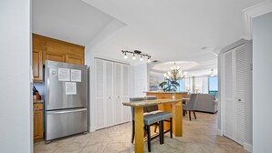 Una cocina moderna con un refrigerador de acero inoxidable, armarios de madera y una zona de comedor con mesa y sillas de madera.