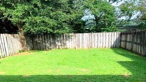 A fenced backyard with a grassy lawn.