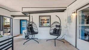 A room with two black wireframe chairs with cushions, a white door, and a window with a view of the outside. - Lakeside Sandlot-New-Wiffle ball field+Hot Tub-Close to Rocker B-Family Fun! (Graford)