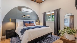 A bedroom with a bed, bedside tables, an air conditioner, a window with curtains, a ceiling fan, and a potted plant. - Lakeside Sandlot-New-Wiffle ball field+Hot Tub-Close to Rocker B-Family Fun! (Graford)