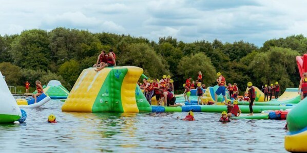 An outdoor water activity area with inflatable structures and people engaged in water games.