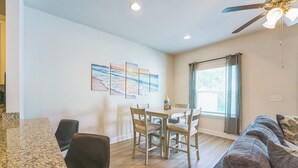 A dining area with a table and chairs, a ceiling fan, and a window with curtains. - Bright & Modern Beach Getaway-Pool+Prime Location (Panama City Beac)