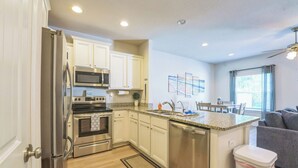 A modern kitchen with stainless steel appliances, white cabinetry, and a central island. - Bright & Modern Beach Getaway-Pool+Prime Location (Panama City Beac)