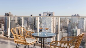 Une terrasse sur le toit, avec des fauteuils en osier, une table ronde et deux verres de vin.
