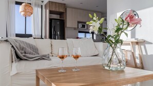 Un salon moderne avec une table basse en bois, deux verres à vin et un vase rempli de fleurs.
