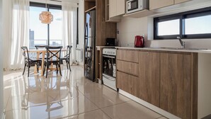 Une cuisine moderne avec des meubles en bois, un four à micro-ondes et une bouilloire rouge.