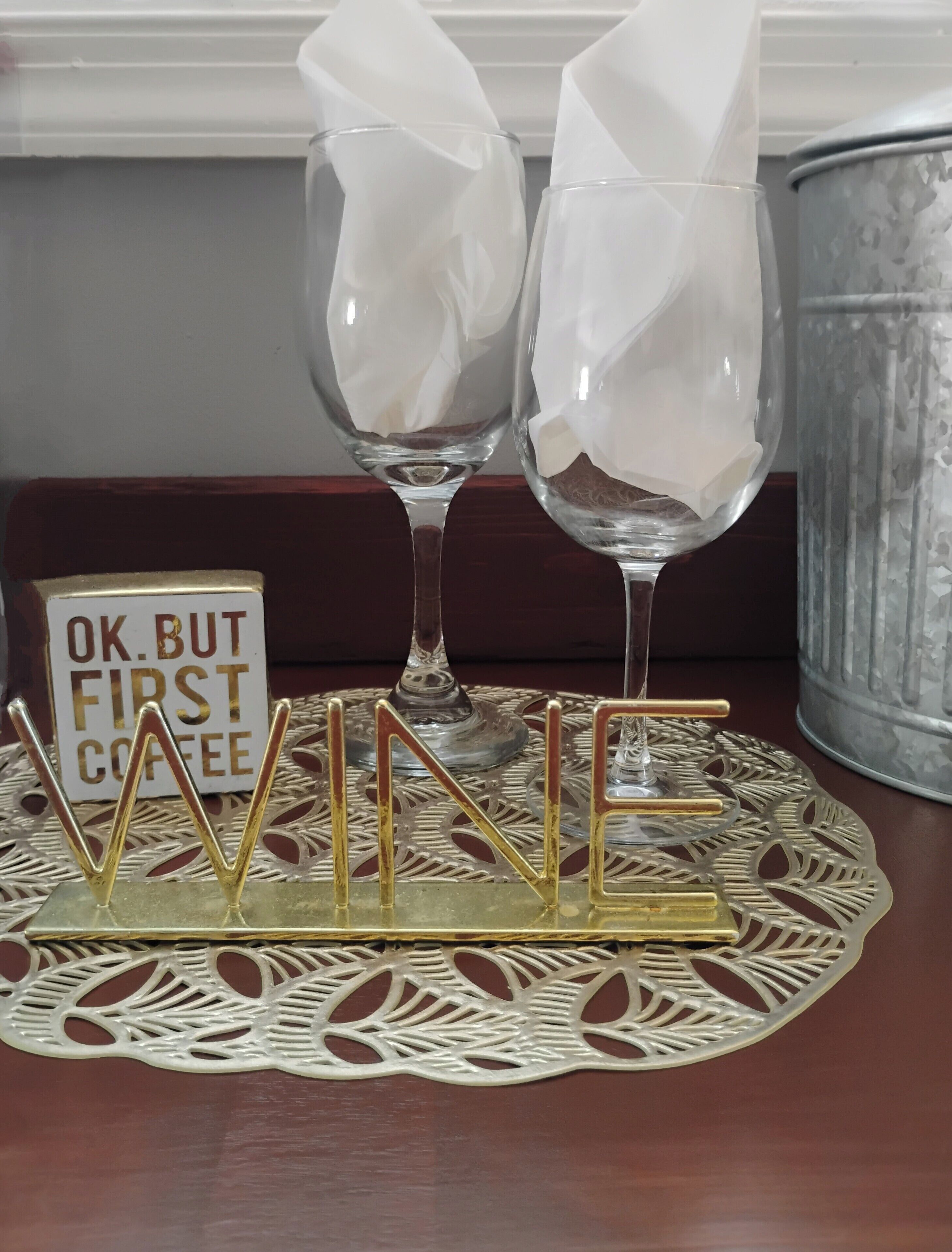 Twee wijnglazen op een decoratief dienblad met de letters ‘WINE’ in goud.