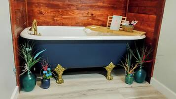 A bathroom with a bathtub, wooden panel walls, and decorative vases on the floor.