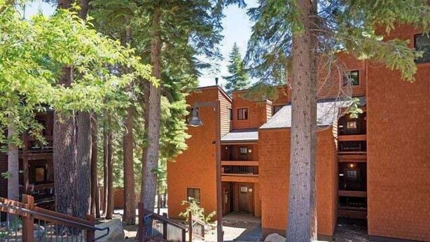 A building with a rustic design, featuring wooden balconies and a stone pathway. - Mountain bikers dream near Gondola in Northstar (Truckee)