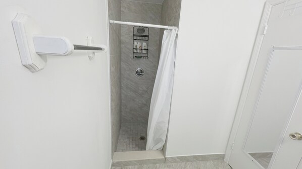 Un baño con ducha, toallero y retrete.