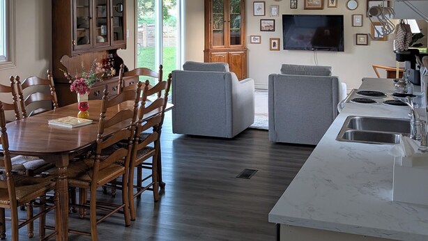 Una cocina moderna con encimera de mármol, un comedor con sillas de madera y una sala de estar con sofás grises.