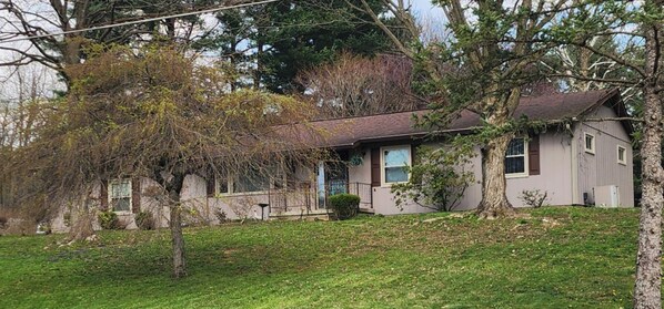Ein Wohnhaus mit Vorgarten, Baum und Garage.