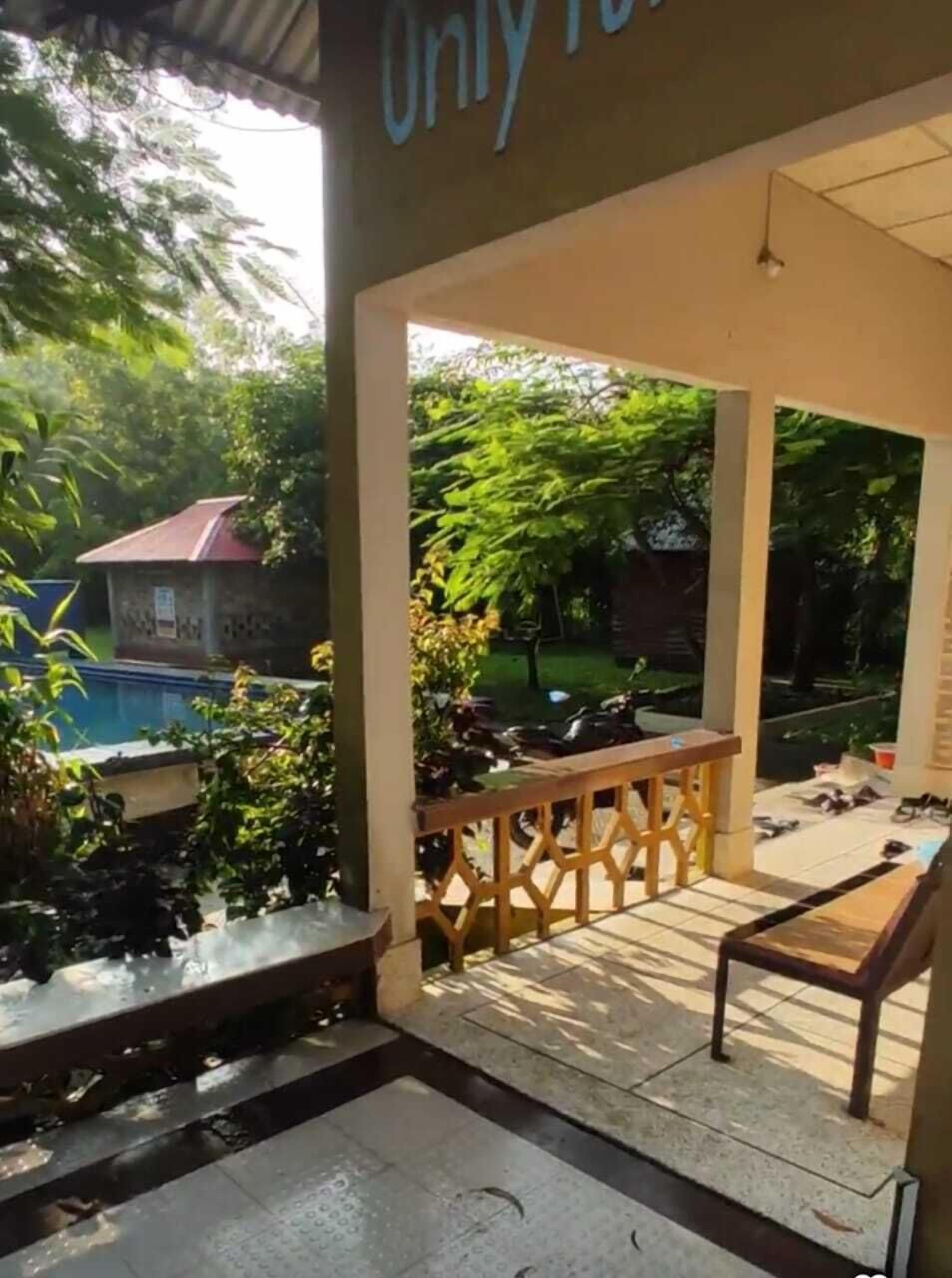 Área externa coberta com um banco de madeira, uma mesa pequena e uma placa com a inscrição 'Apenas para'.