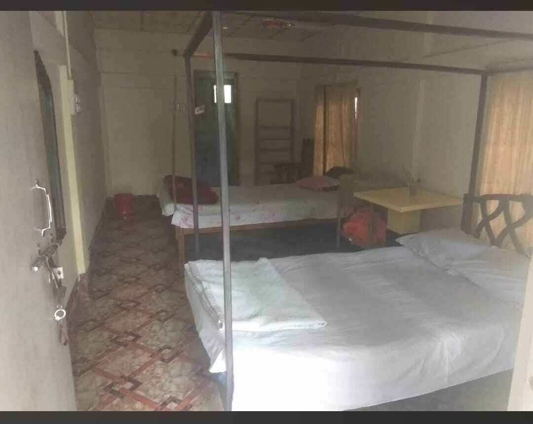 Ein Zimmer mit zwei Betten, einem kleinen Tisch und einem Spiegel.