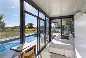 A modern bedroom with a large glass wall, a pool, and a white sofa. - Classic Contemporary Country Charm close to Town Centre (Martinborough)