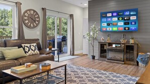 Uma sala de estar moderna com um sofá de couro, uma mesa de centro, uma lareira e uma televisão exibindo diversos serviços de streaming.