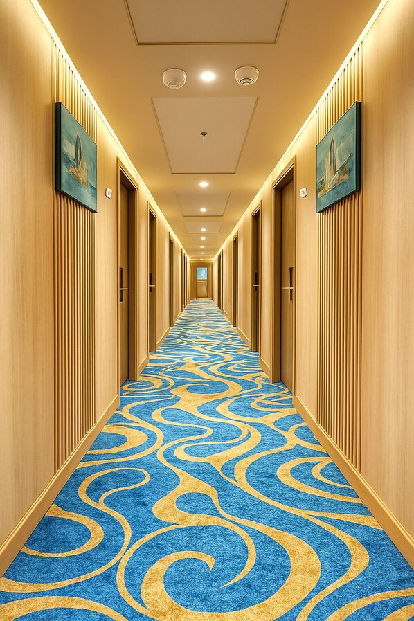 A hotel hallway with a blue carpet featuring a golden swirl pattern, wooden paneling on the walls, and framed artwork above the doors. - Nile Cruise Royal Adventure 3 every Friday from Aswan 3 nights and every Monday from Luxor 4 nights. (Aswan)
