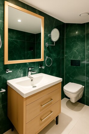 A modern bathroom with a marble backsplash, a wooden vanity with drawers, a white sink, a round mirror, a toilet, and a wall-mounted toilet paper holder. - Nile Cruise Royal Adventure 3 every Friday from Aswan 3 nights and every Monday from Luxor 4 nights. (Aswan)