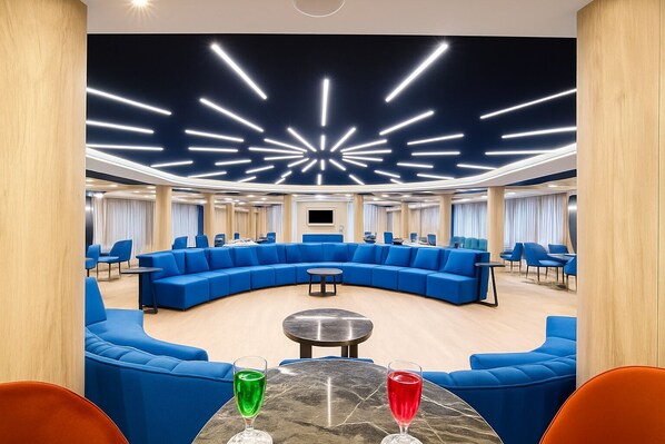 A modern hotel lobby with a curved blue sofa, round tables, and a ceiling with starburst lighting. - Nile Cruise Royal Adventure 3 every Friday from Aswan 3 nights and every Monday from Luxor 4 nights. (Aswan)