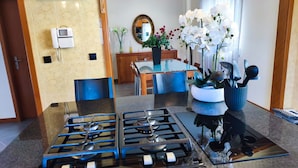 A modern kitchen with a gas stove, a built-in oven, and a dining area with a glass table and chairs.