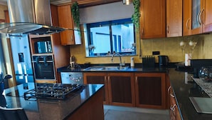 A modern kitchen with wooden cabinets, a gas stove, stainless steel appliances, and a window with a view.