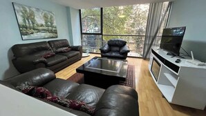 A living room with a sofa, armchair, coffee table, TV, and a white entertainment unit. - Close to the best places in Polanco (Ciudad de México)