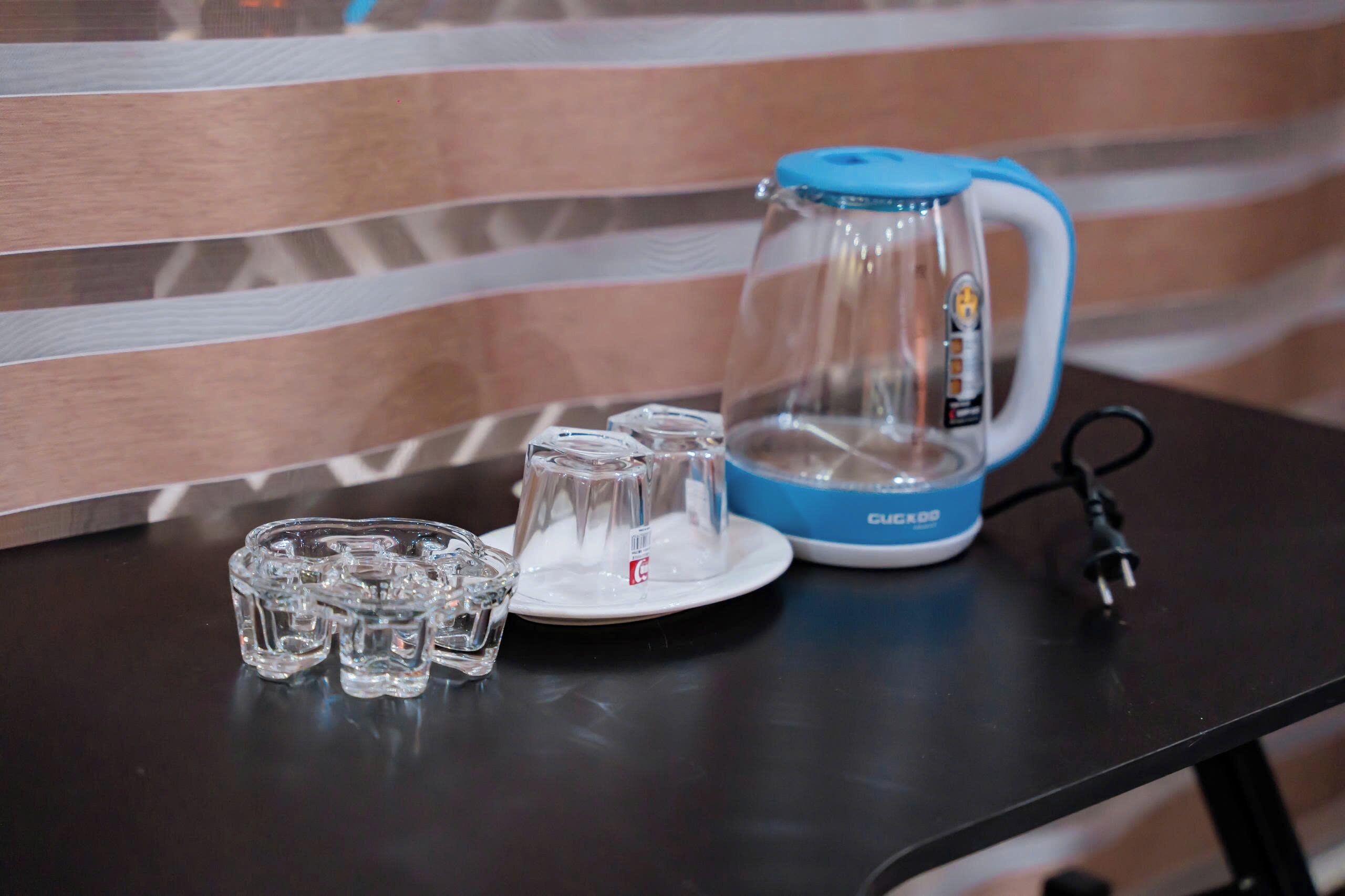 A table with a kettle, a plate, and a set of glasses.