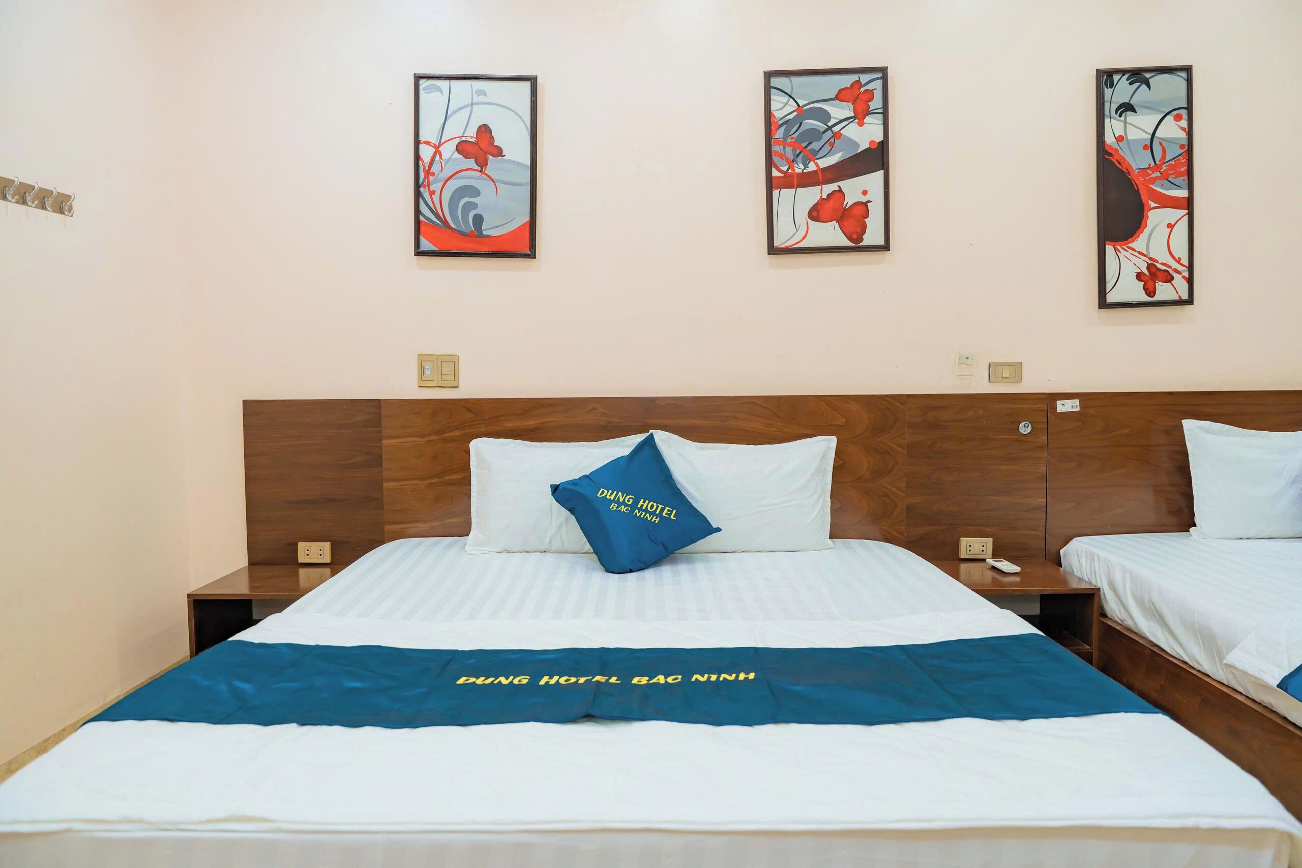 Una habitación de hotel con dos camas, un cabecero de madera y obras de arte en las paredes.