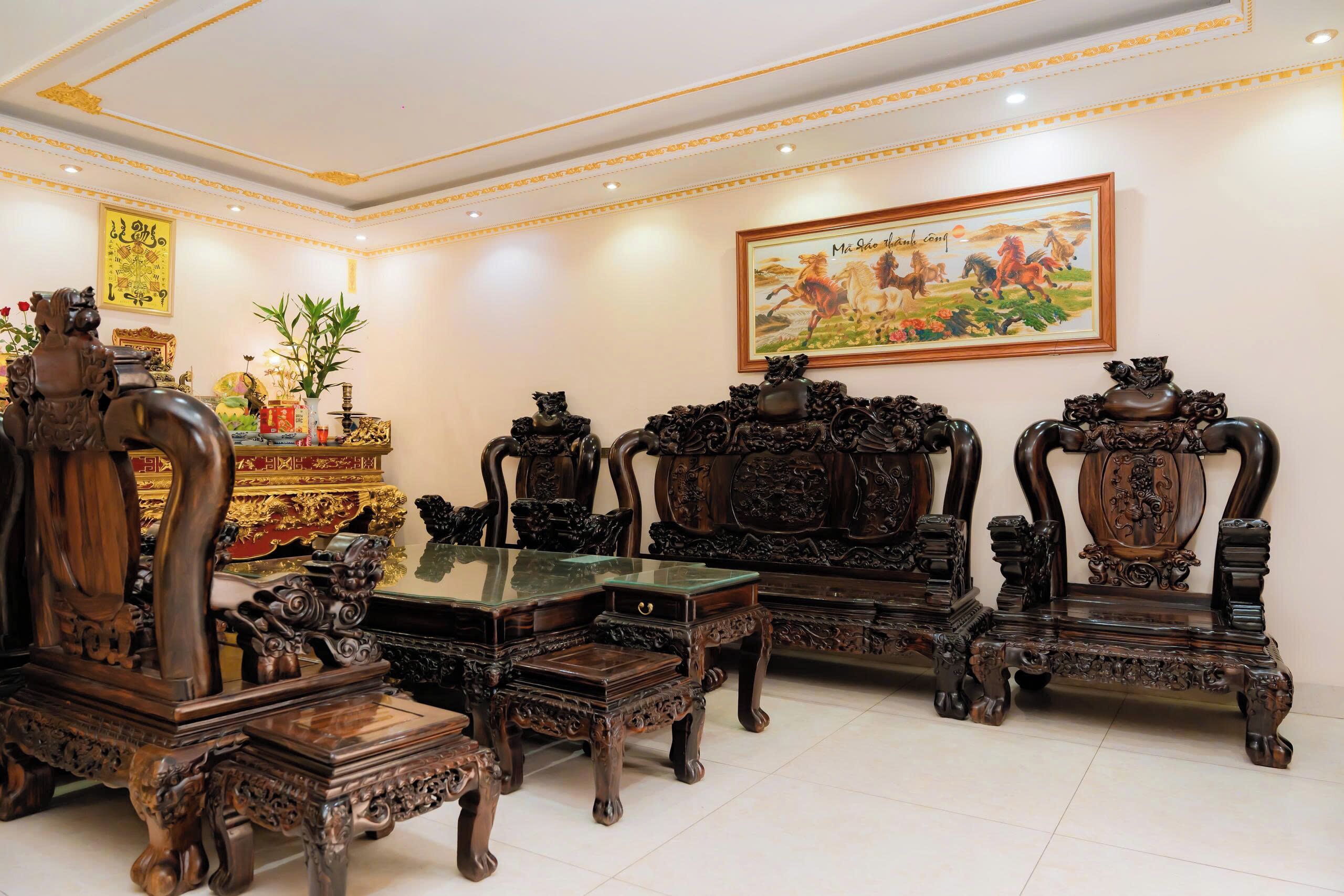 A traditional room with ornate wooden furniture, a painting on the wall, and a decorative altar.