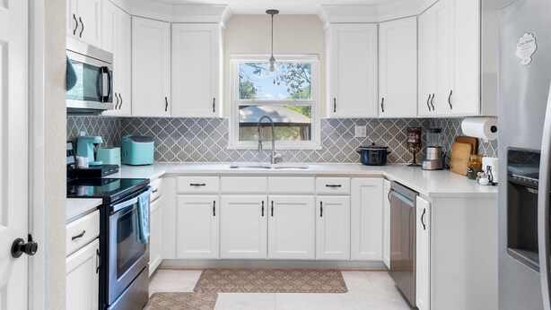 A modern kitchen with white cabinets, a built-in microwave, a sink, and a refrigerator. - Escape by Beaches & Blue Angels (Pensacola)