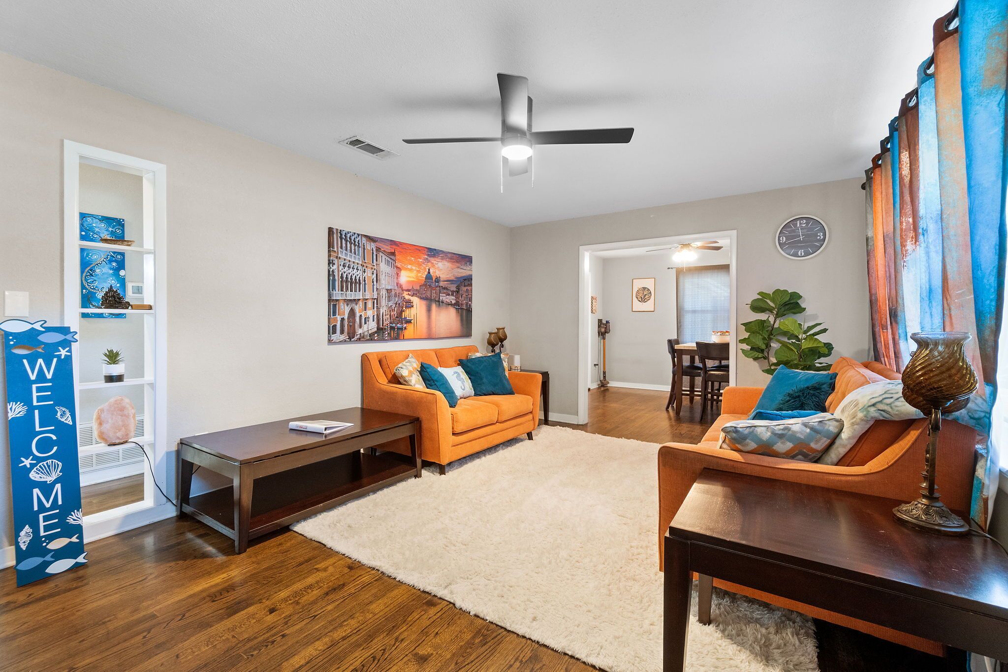 Uma sala de estar moderna com sofá, mesa de centro, rack para TV e um detalhe decorativo na parede.