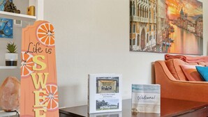 A reception desk with a sign reading 'Life is SWEET,' a framed photo of a room, and a 'Welcome!' sign. - Escape by Beaches & Blue Angels (Pensacola)