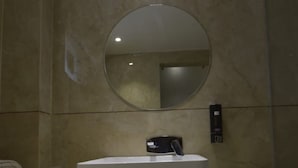 A bathroom with a white sink, a round mirror, and a towel on the counter.