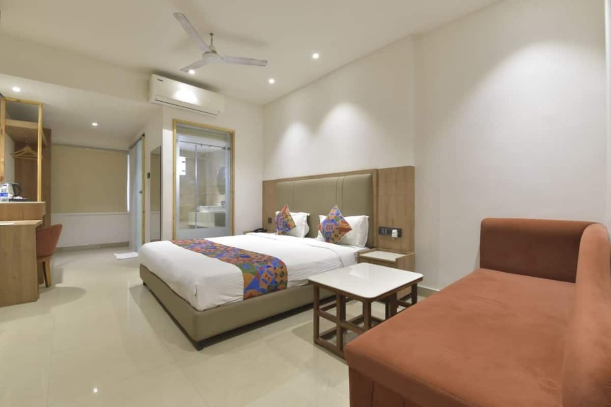 A hotel room with a bed, bedside tables, a desk, a chair, and a ceiling fan.