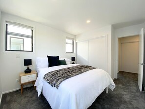A bedroom with a bed, bedside tables, and a door. - Salisbury courtyard stay with fibre Wi-Fi in Christchurch (Christchurch)