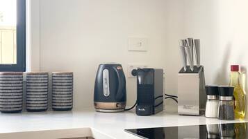 A kitchen with a kettle, a Breville coffee maker, and three patterned containers on the counter.