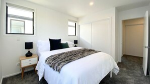 Un dormitorio con cama, mesitas de noche y una puerta.