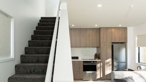 Un intérieur moderne avec un escalier menant à une cuisine, un coin repas avec un canapé et un réfrigérateur.