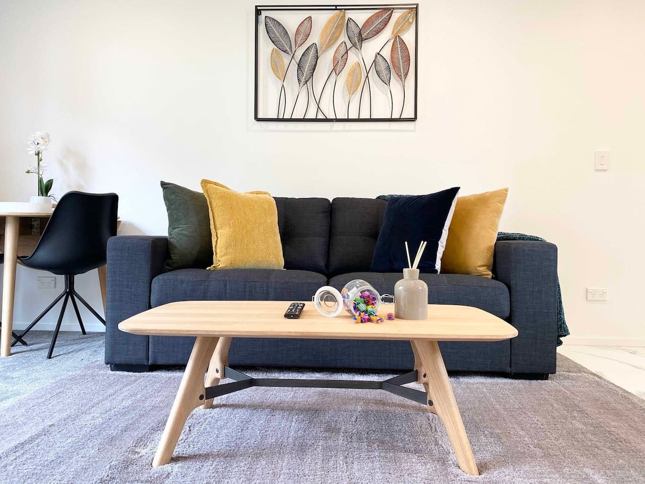 A modern living room with a grey sofa, a wooden coffee table, and a framed artwork on the wall.