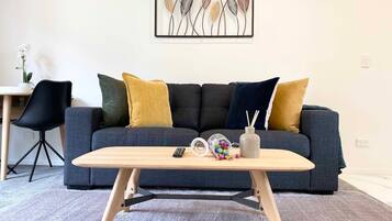 A modern living room with a grey sofa, a wooden coffee table, and a framed artwork on the wall.