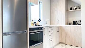 A modern kitchen with stainless steel appliances, wooden cabinets, and a marble floor.