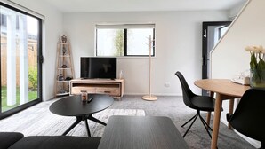 Una sala de estar moderna con televisor, mesa de comedor y sofá.
