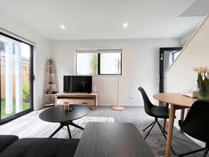 Una sala de estar moderna con televisor, mesa de comedor y sofá.